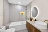 Bathroom featuring a wood-finish vanity with a vessel sink, quartz-style countertop, a walk-in shower with a glass panel and integrated recessed niche