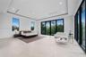 Serene bedroom with tray ceiling and walls of glass framing the treetops
