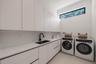 Minimalist utility room featuring floor-to-ceiling white cabinetry, a composite countertop with an integrated basin, a matte black gooseneck faucet, a