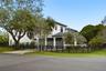 Two-story exterior featuring white stucco finish, a multi-car garage with dark-toned doors, black metal fencing, and mature trees