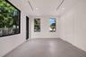 Neutral-toned oversized tile flooring, high ceilings with recessed linear lighting, and expansive black-framed windows