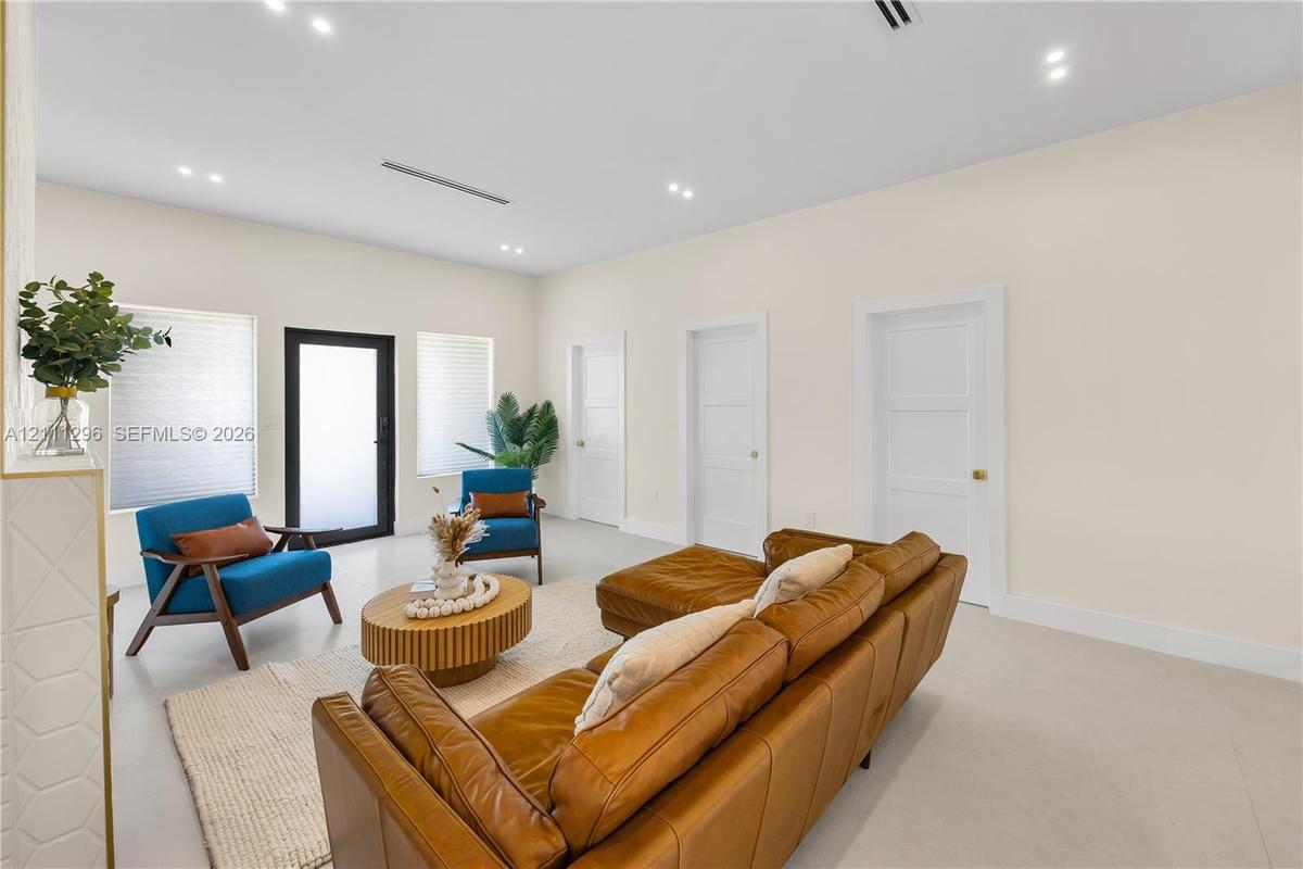 Neutral-toned interior featuring smooth-finish flooring, recessed ceiling lighting, three paneled interior doors, and a black-framed glass-panel entry