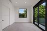 Interior room featuring neutral stone-finish flooring, recessed lighting, black-framed windows, and a sliding glass door providing access to a balcony