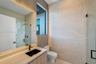 Bathroom featuring large-format stone-finish wall tiles, wood-finish vanity cabinetry, a rectangular vessel sink with matte black hardware, and an exp