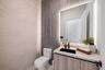 Custom vanity with wood-finish cabinetry, integrated rectangular basin, matte black faucet, and textured vertical-slat feature wall with backlighting