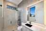 Walk-in shower with floor-to-ceiling tile, frameless glass enclosure, wall-mounted rain shower head, textured accent wall, and floating vanity with in