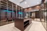 Boutique style closet with glass front cabinetry, lighting, and a center island