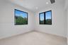 Interior room featuring high ceilings, large-format tile flooring, and dual windows with black frames