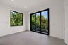 Interior space featuring large-format grey tile flooring, black-framed picture windows, black-framed sliding glass doors, and recessed ceiling lightin