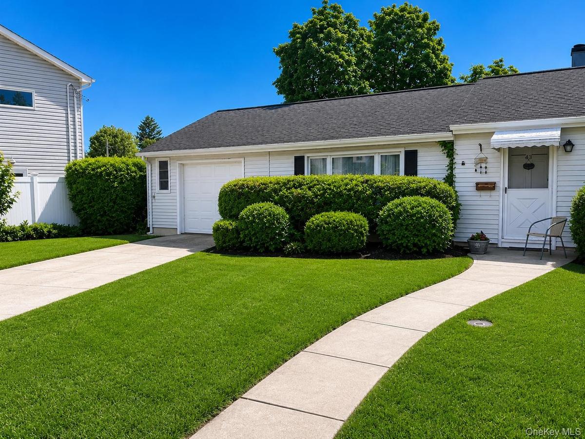 White siding exterior with a dark shingle roof, complemented by a concrete driveway and walkway
