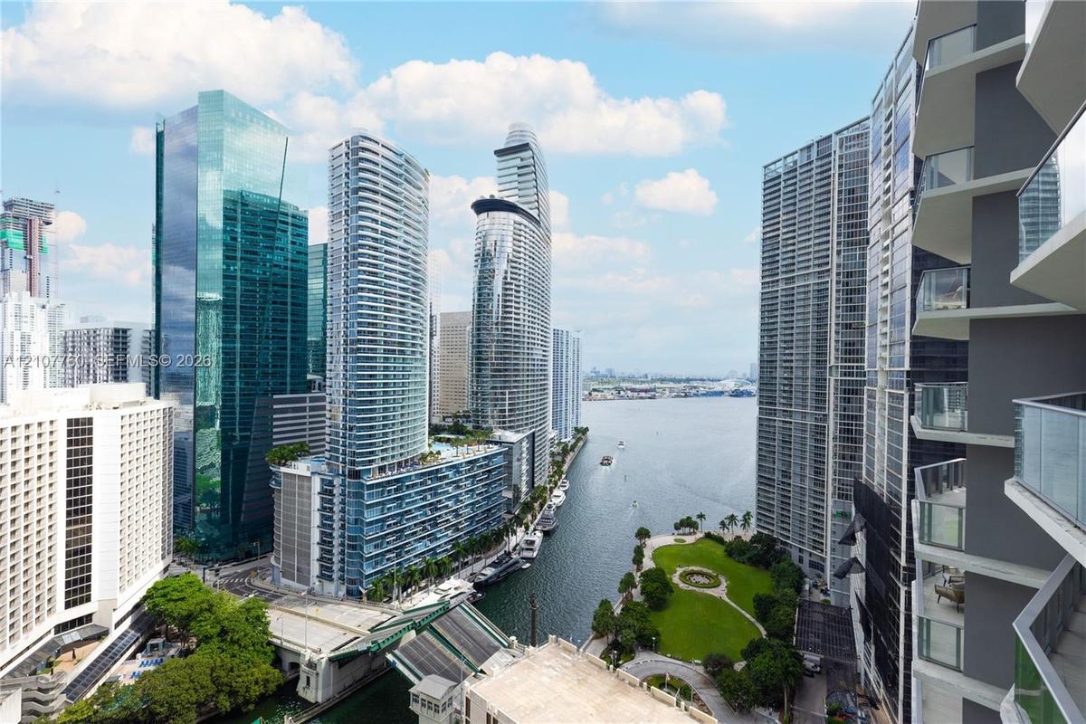 Private balconies with glass railings overlooking a waterfront cityscape and public green space