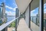 Expansive covered balcony featuring large-format tile flooring, glass panel railings, and floor-to-ceiling sliding glass entry points