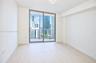 Floor-to-ceiling sliding glass doors, neutral tile flooring, and urban skyscraper scenery