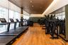 Fitness center featuring wood-finish flooring, floor-to-ceiling windows with roller shades, recessed cove lighting, and a full-length wall mirror