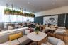Common area featuring floor-to-ceiling windows with sheer drapery, a stone-topped bar with brass-tone pendant hardware, integrated overhead planters, 