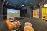 Dedicated recreation room featuring a built-in golf simulator, integrated projection system, recessed cove lighting, and floor-to-ceiling drapery
