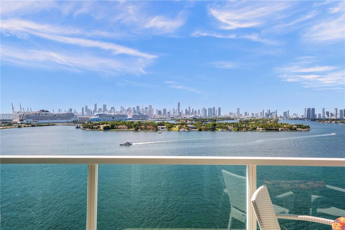 Balcony featuring a glass panel railing and panoramic waterfront and city skyline scenery