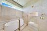 Freestanding white soaking tub with a floor-mounted faucet, floor-to-ceiling stone wall tiling, integrated recessed niche with accent lighting, built-
