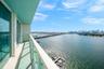 Waterfront balcony with floor-to-ceiling glass doors, expansive bay vistas, and modern glass railings