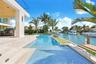 Waterfront lap pool featuring tiled finishes, stone decking, and a built-in outdoor kitchen