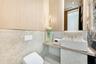Wall-mounted toilet with a concealed flush plate, stone-tiled walls, light wood paneling, stone vanity with a vessel sink, and integrated LED accent l