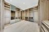Custom built-in wood-finish cabinetry featuring extensive shelving, hanging rods, integrated mirrors, and recessed ceiling lighting throughout