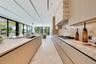 Custom wood-finish cabinetry, expansive stone-topped kitchen island with waterfall edge, integrated stainless steel appliances, and floor-to-ceiling g