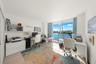 Floor-to-ceiling sliding glass door, balcony with glass railing, wood-finish flooring, and built-in wall cabinetry