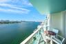 Covered balcony featuring glass railing and expansive water and city skyline outlooks