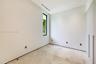 Minimalist room featuring natural stone flooring, floor-to-ceiling built-in cabinetry, recessed lighting, and a vertical window