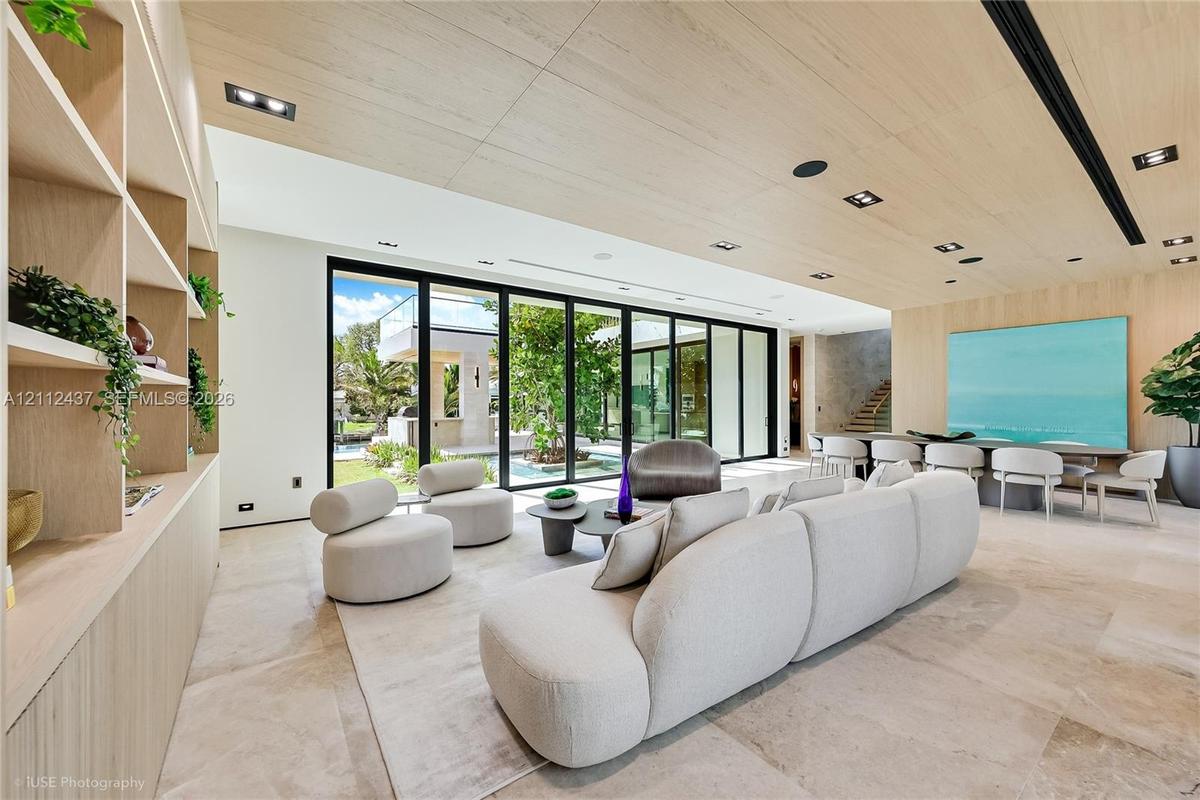 Open-concept interior featuring natural stone flooring, expansive floor-to-ceiling glass sliding doors, wood-paneled ceiling with recessed lighting, a