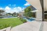 Outdoor terrace featuring a reflective water feature with a central tree, built-in stone kitchen, glass-railed balcony, and retractable wall panels