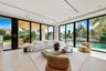 Living area featuring floor-to-ceiling glass sliding doors, recessed lighting, built-in light-tone cabinetry, and natural stone flooring