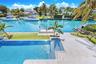 Waterfront estate featuring a paved terrace, swimming pool with integrated sun shelf, private boat dock, and manicured landscaping