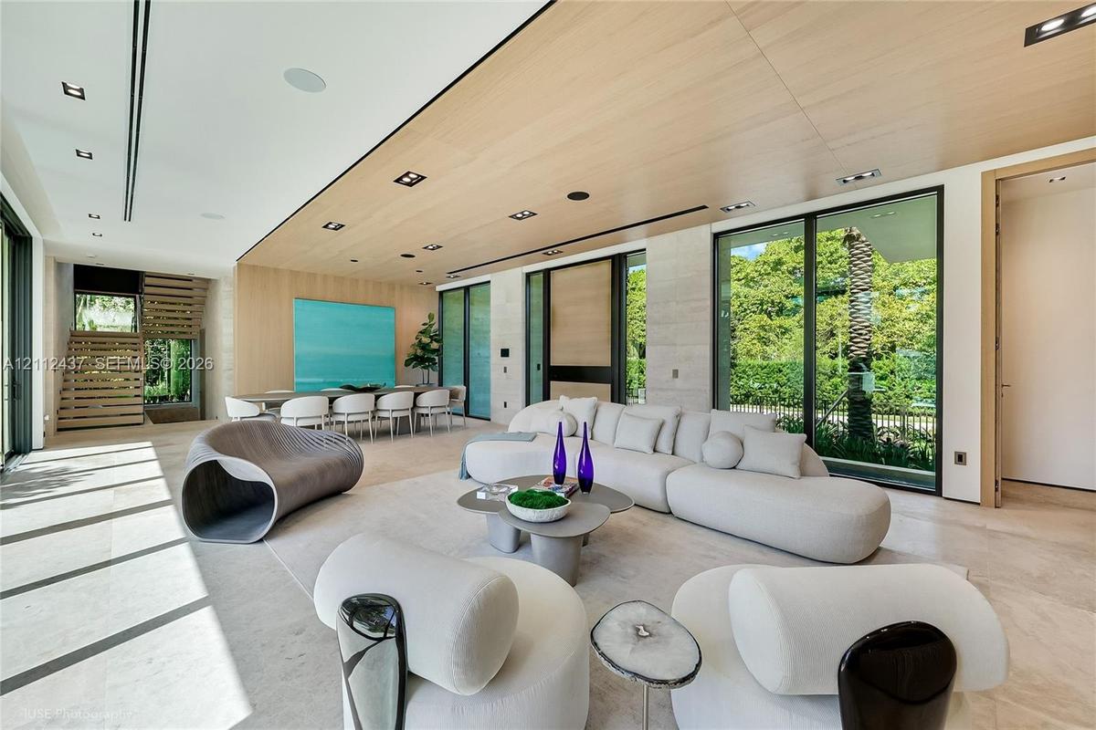 Open-concept living space featuring wood-clad ceilings, floor-to-ceiling glass sliding doors, stone-finish flooring, and built-in light-tone wood shel