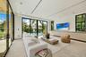 Custom light-finish cabinetry, natural stone backsplash and range hood surround, integrated stainless steel appliances, stone slab countertop, and rec