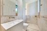 Floating vanity with integrated sink and wall-mounted faucet, walk-in shower with glass partition, floor-to-ceiling tiled walls, and recessed lighting