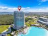 High-rise residential tower featuring a glass facade, private balconies, and proximity to an expansive man-made lagoon with a sandy beach