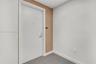 Entryway featuring a solid door with integrated peephole and metal hardware, accent wall with vertical wood-finish paneling, and neutral carpeting