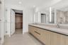 Floating vanity with dual rectangular undermount sinks, sleek wood-finish cabinetry, expansive wall-to-wall mirror with integrated lighting, and a wal