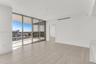 Open-concept interior featuring floor-to-ceiling sliding glass doors, a covered balcony, large-format tile flooring, and a stone-surface counter