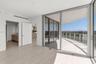 Floor-to-ceiling glass walls, expansive covered balcony, wood-finish flooring, and recessed ceiling lighting
