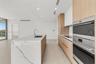 Kitchen featuring a waterfall-edge island with stone-finish countertops, wood-finish cabinetry, built-in stainless steel wall ovens, wood-finish floor