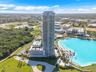 High-rise residential tower featuring a cylindrical glass facade, surrounding private balconies, a ground-level swimming pool, and immediate proximity