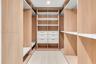 Custom walk-in closet featuring floor-to-ceiling wood-finish cabinetry, built-in shelving, integrated hanging rods, and stacked drawer storage with cl