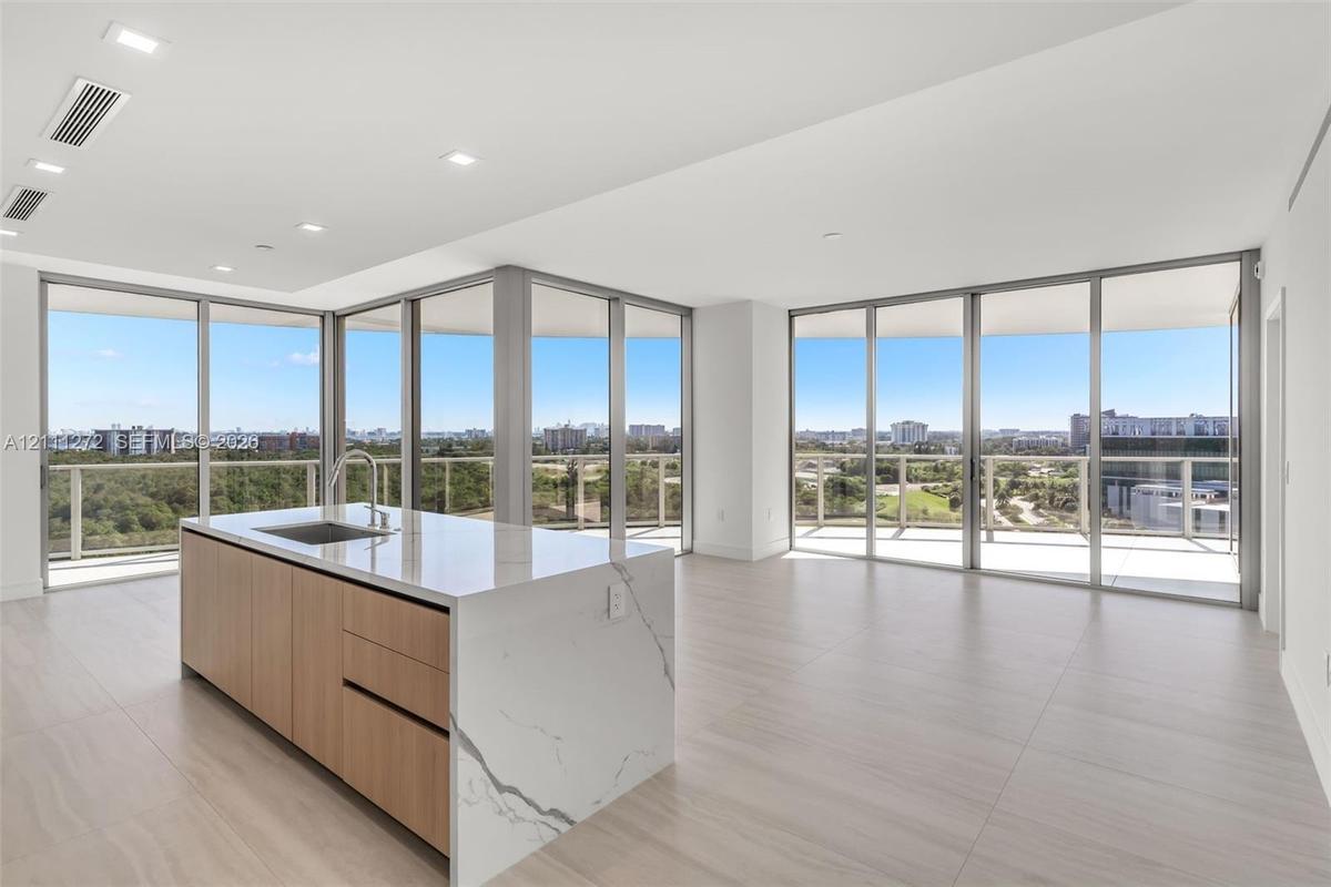 Modern kitchen island featuring waterfall-edge stone countertop, wood-finish cabinetry, and built-in stainless steel sink with gooseneck faucet, set w