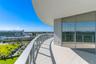 Curved balcony featuring light-toned tile flooring, glass panel railings, and floor-to-ceiling glass sliding doors