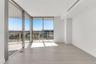 Floor-to-ceiling glass walls, wrap-around balcony with metal railing, wood-finish flooring, and recessed ceiling lighting