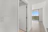 Floor-to-ceiling glass sliding doors, private balcony, neutral large-format tile flooring, and solid-core interior doors