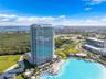 High-rise residential tower featuring a glass facade, expansive balconies, ground-level swimming pool, and an integrated recreational water feature